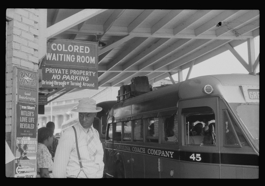 Man standing under "colored waiting room" sign.