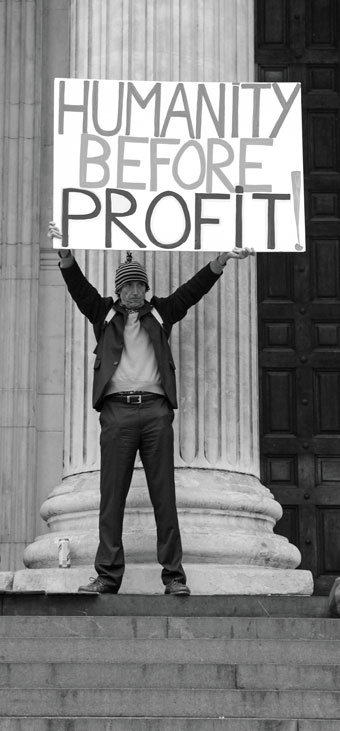 Man holding sign that says "humanity before profit"