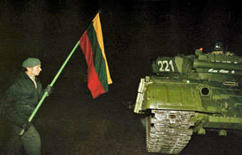Man with Lithuanian flag in front of Soviet tank