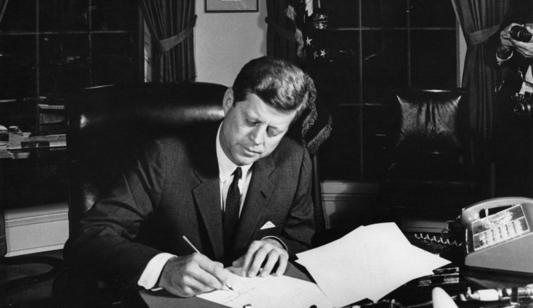 John F. Kennedy sitting at his desk writing