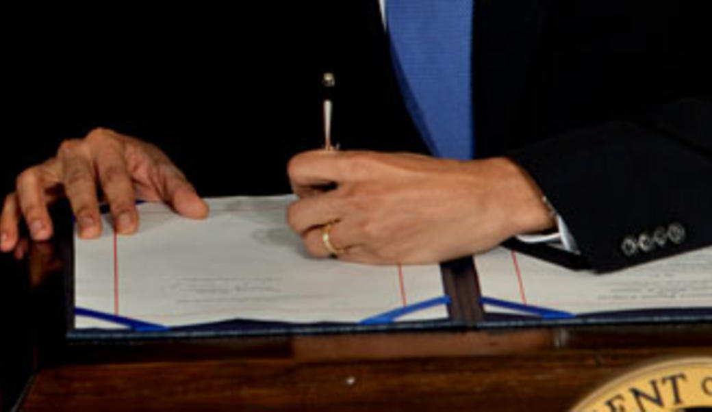 Close up of Barack Obama signing a bill