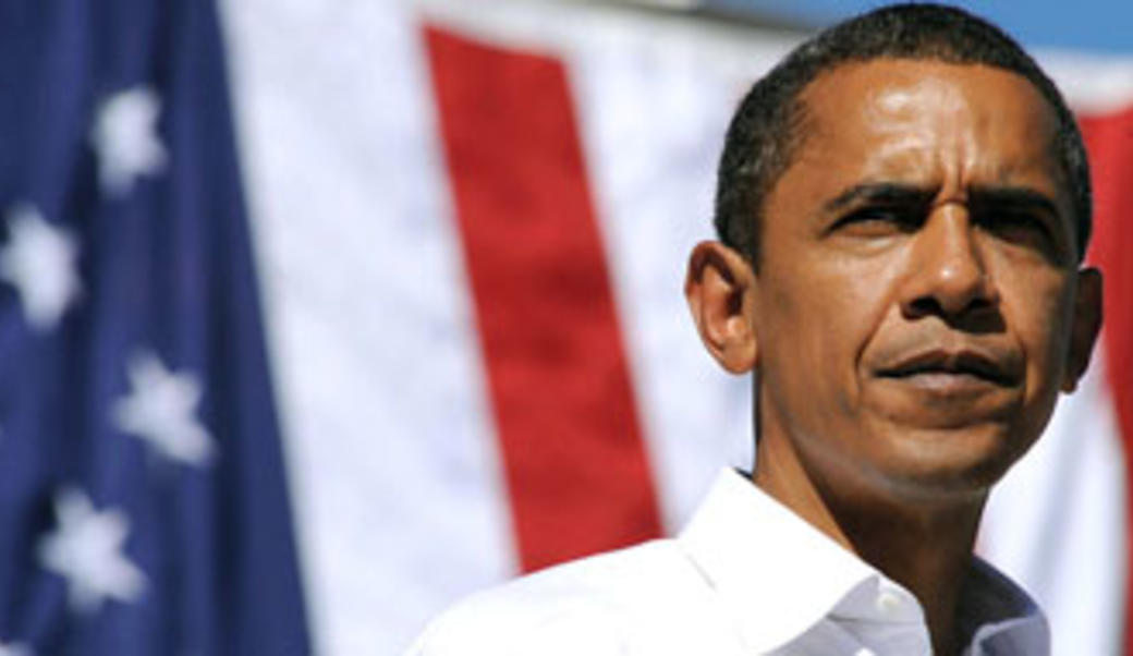 President Barack Obama stands in front of a U.S. flag