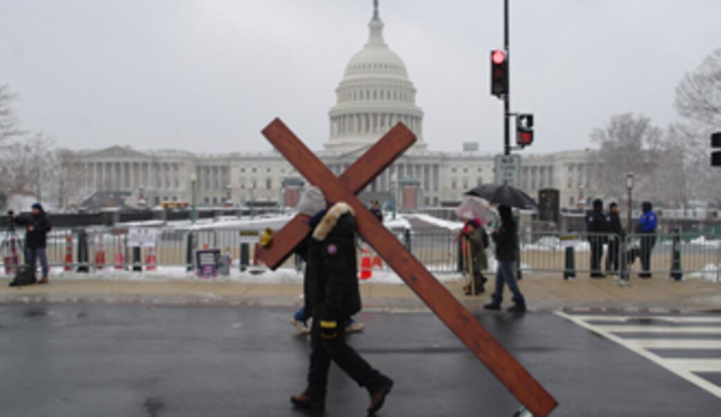 Man wheeling cross in front of US Capitol